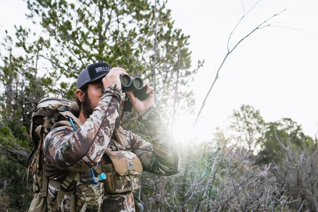 Josh from Dialed in Hunter looking through binoculars while Western hunting.