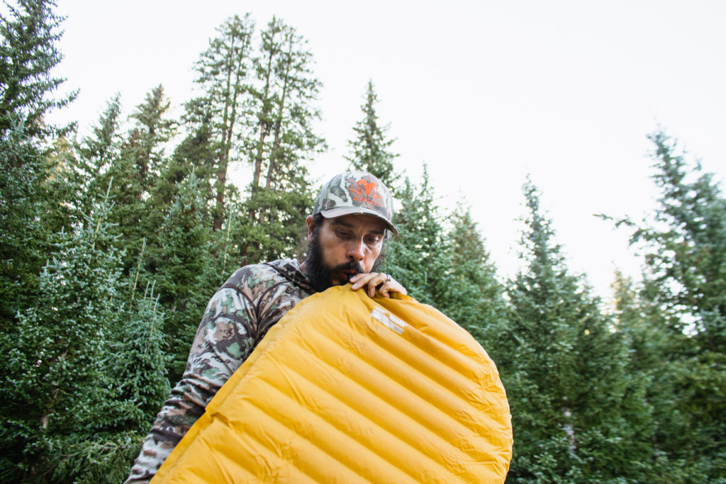 Josh Kirchner from Dialed in Hunter blowing up an inflatable sleeping pad on a backpack hunt in Colorado
