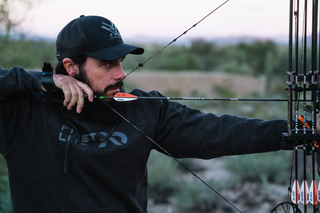 Josh Kirchner from Dialed in Hunter at full draw at an archery range in Phoenix, Arizona