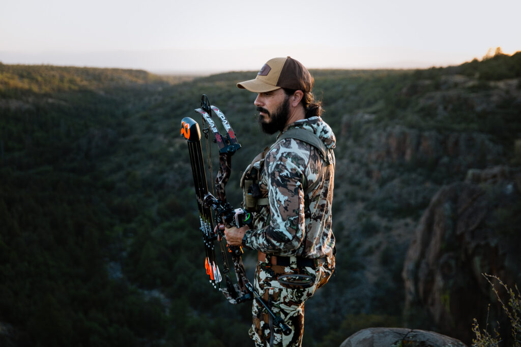 Josh Kirchner from Dialed in Hunter standing on the edge of a cliff bowhunting for black bears in Arizona