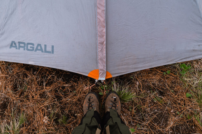 Standing at the door of a tent in the backcountry