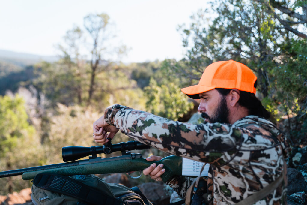 Josh Kirchner adjusting his rifle scope on a Fall bear hunt in Arizona