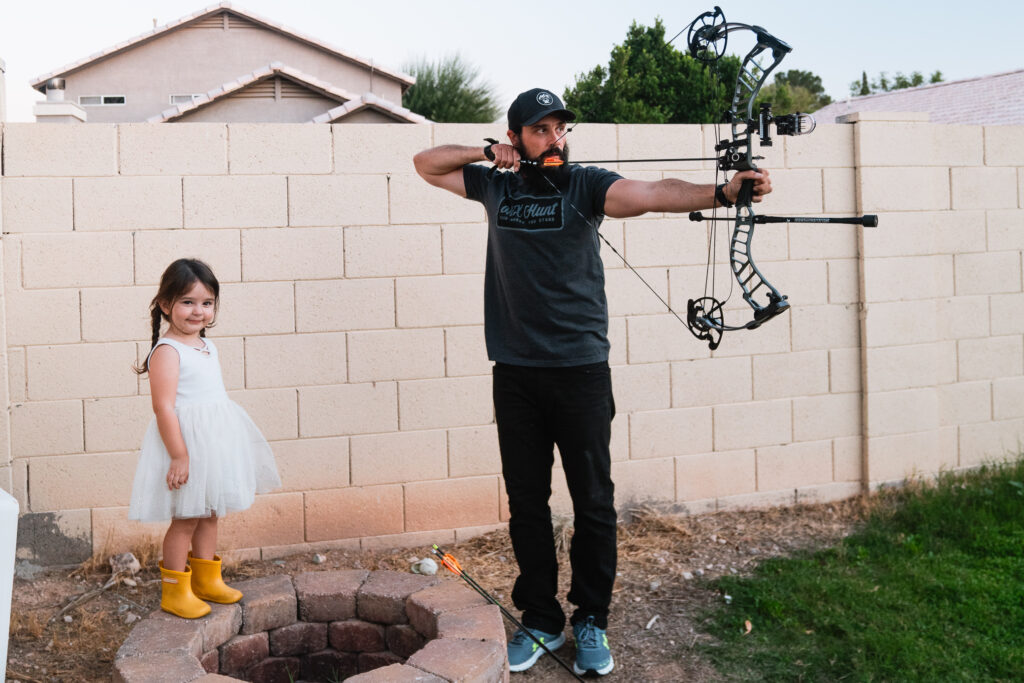 Dad shooting his bow with his daughter by his side