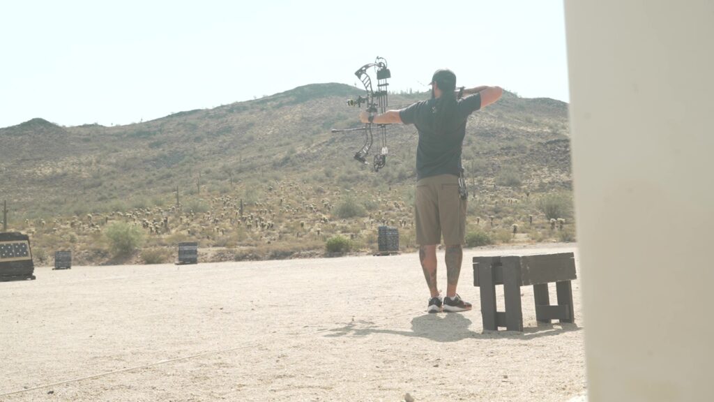 Josh Kirchner practicing shooting his bow with new arrows at the archery range