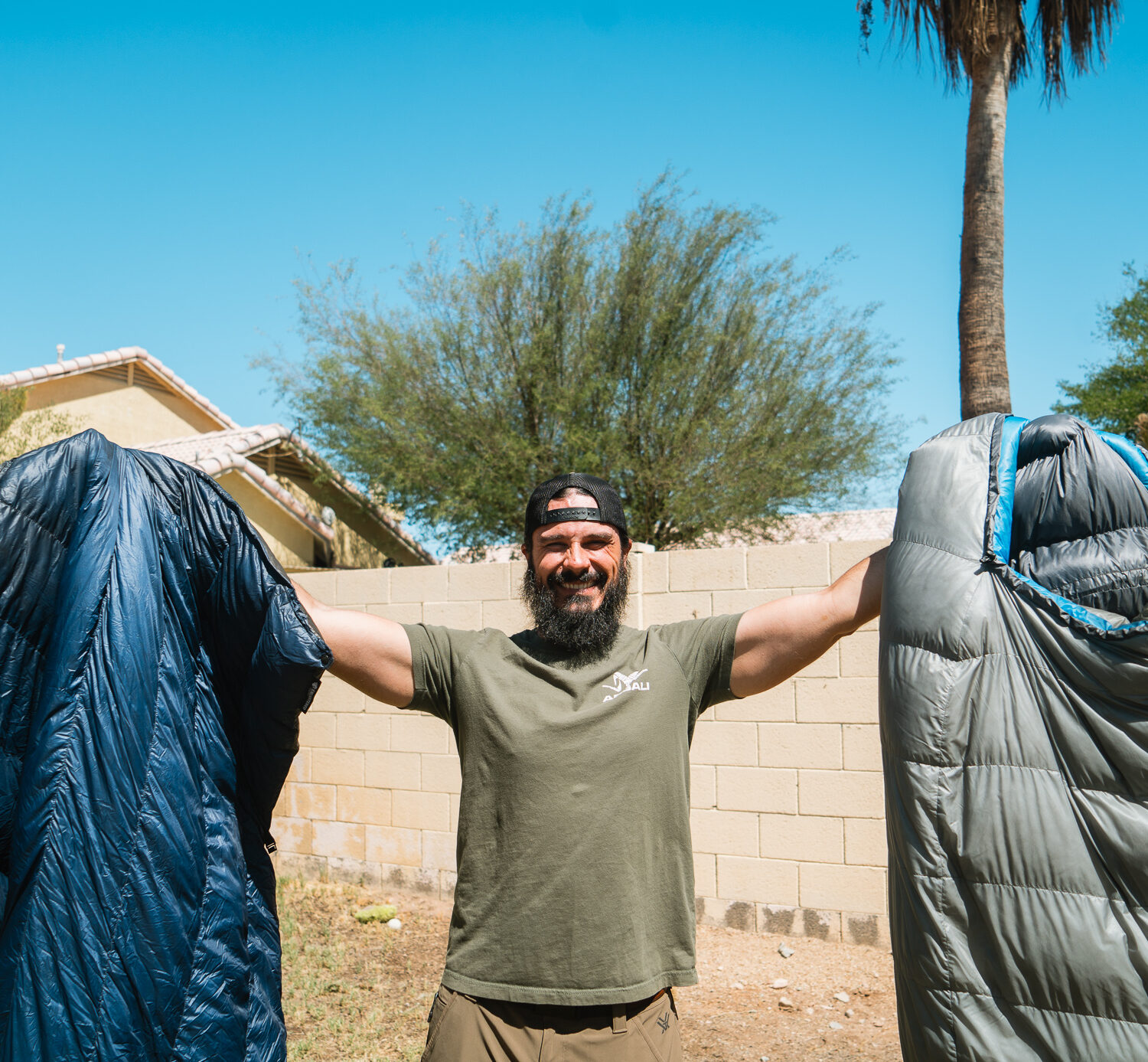 Josh Kirchner from Dialed in Hunter holding up a quilt and sleeping bag for backpack hunting