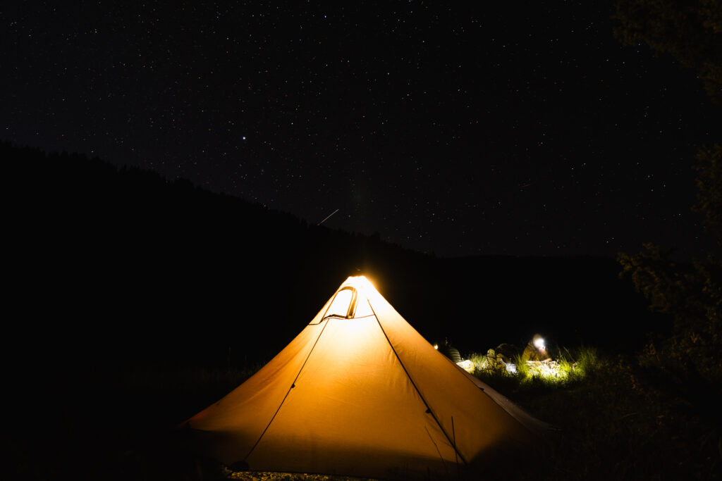 Josh Kirchner sitting near his tent in the backcountry on an elk hunt in Colorado