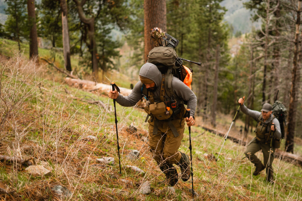 Josh Kirchner hiking up a ridge with company in tow on a backpack hunt in Idaho for black bears