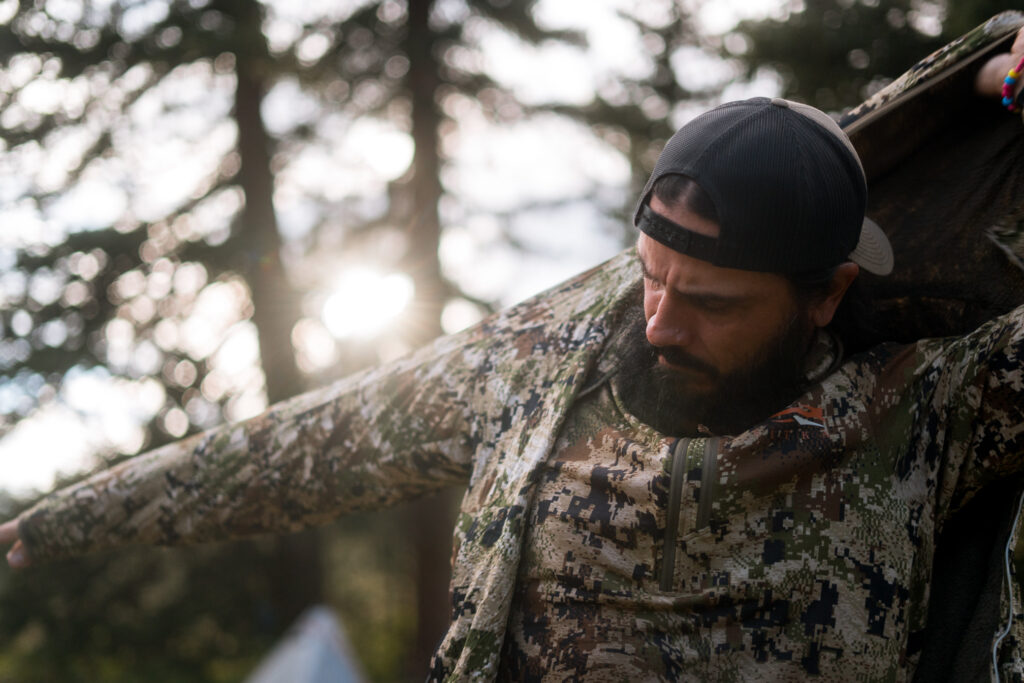 Josh Kirchner from Dialed in Hunter putting on a mid-layer of clothing on a backpack hunt for elk in Colorado