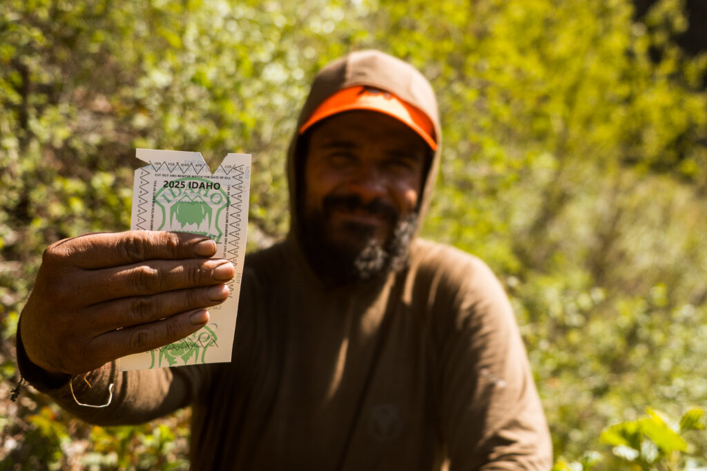 Josh Kirchner holding a notching black bear tag in the backcountry of Idaho